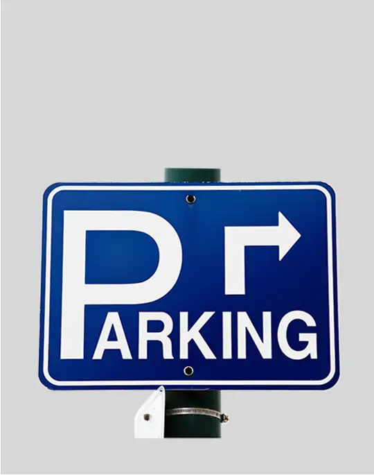 parking-sign Blue rectangular parking sign with rounded corners, featuring a large white “P,” the word “PARKING,” and a white right-pointing arrow, mounted on a green pole.