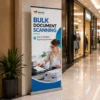 Custom roll-up banner promoting bulk document scanning services displayed in a modern shopping mall.