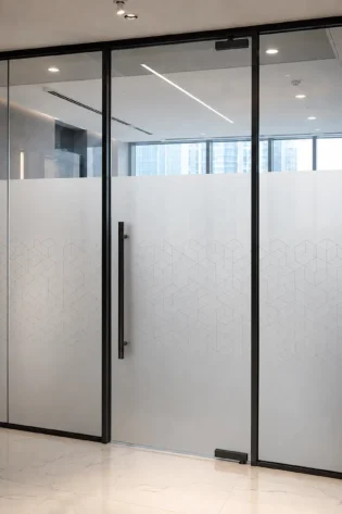 Frosted glass office partition with a subtle geometric pattern and black framing.