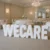 Large freestanding white 3D letters spelling “WECARE” displayed in an elegant indoor event venue.