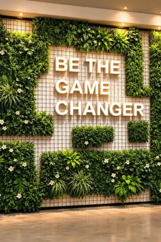 Front view of a custom artificial grass wall backdrop with floral greenery and 3D branded text.