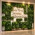 Front view of a custom artificial grass wall backdrop with floral greenery and 3D branded text.