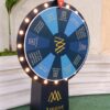 LED spin the prize wheel with Amaar Jewels branding placed at an outdoor venue, featuring illuminated lights, promotional prize segments, and a sturdy display stand for events and activations.
